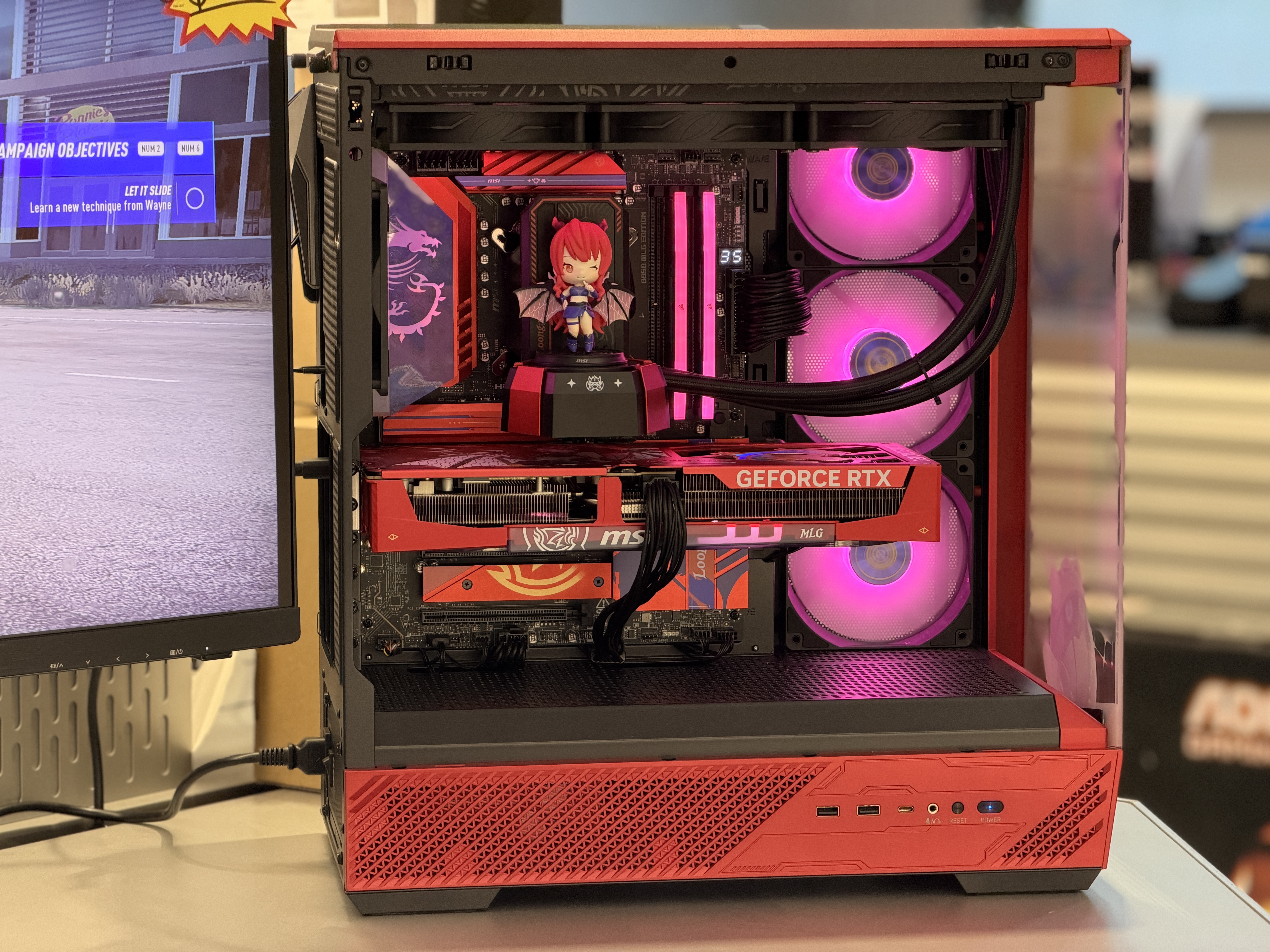 Custom gaming PC set up next to a monitor displaying a game